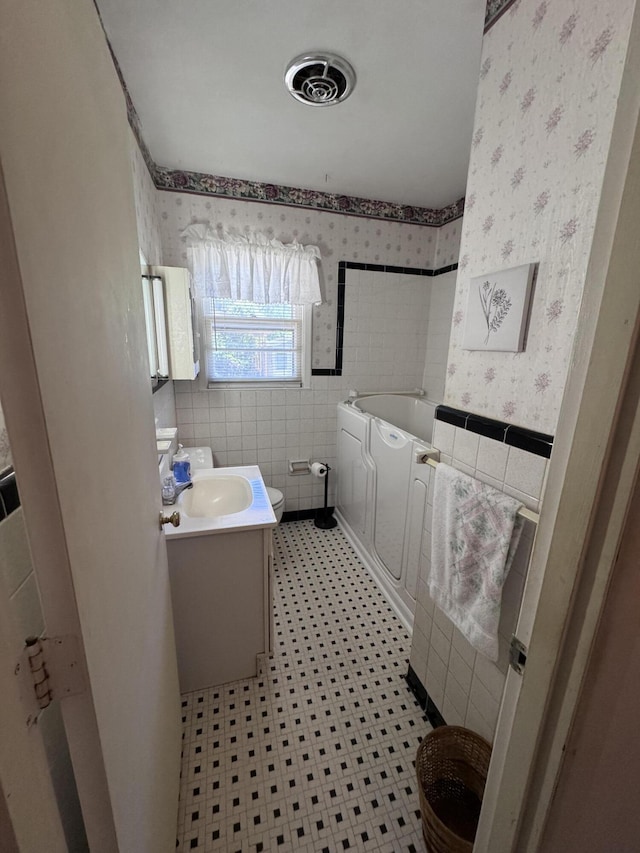 686 W Pine St, Varnville, SC 29944 - bathroom featuring wallpapered walls, a garden tub, vanity, toilet, and tile walls
