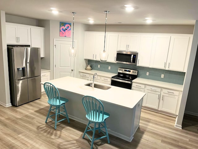 kitchen with appliances with stainless steel finishes, a sink, light wood-type flooring, tasteful backsplash, and recessed lighting