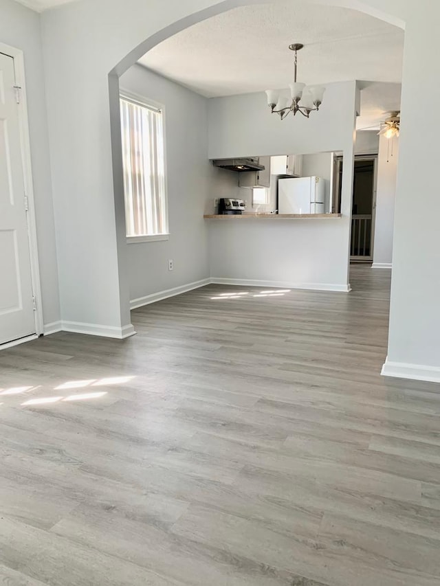 105 S Merriman Rd, Georgetown, SC 29440 - unfurnished living room featuring arched walkways, wood finished floors, a chandelier, and ceiling fan