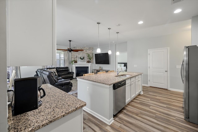 111 Nolin Rd, Moncks Corner, SC 29461 - kitchen with appliances with stainless steel finishes, light wood-style flooring, a ceiling fan, white cabinetry, and a fireplace