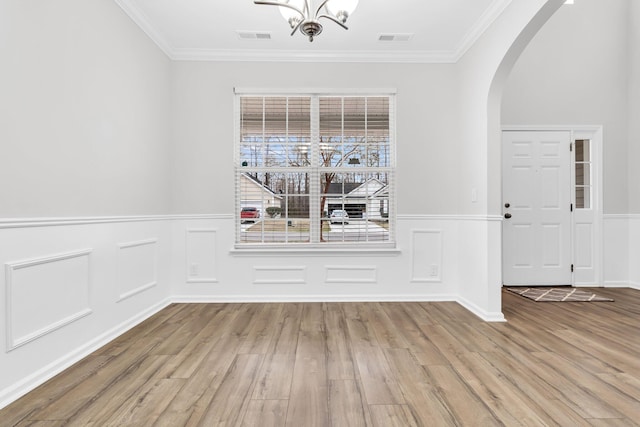 unfurnished dining area featuring crown molding, light hardwood / wood-style flooring, and a chandelier