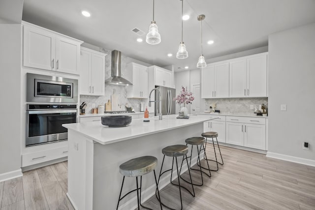 1387 Thin Pine Dr, Johns Island, SC 29455 - kitchen with stainless steel appliances, wall chimney range hood, tasteful backsplash, light wood-type flooring, and light countertops