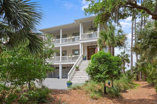 coastal inspired home featuring a balcony, stairway, a porch, and stucco siding