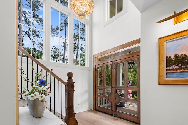 foyer entrance featuring an inviting chandelier, stairs, plenty of natural light, and wood finished floors