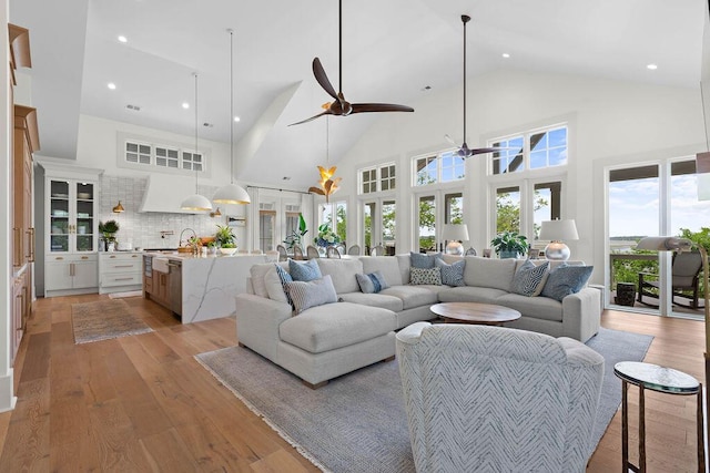 living room with light wood-style flooring, high vaulted ceiling, a ceiling fan, and recessed lighting