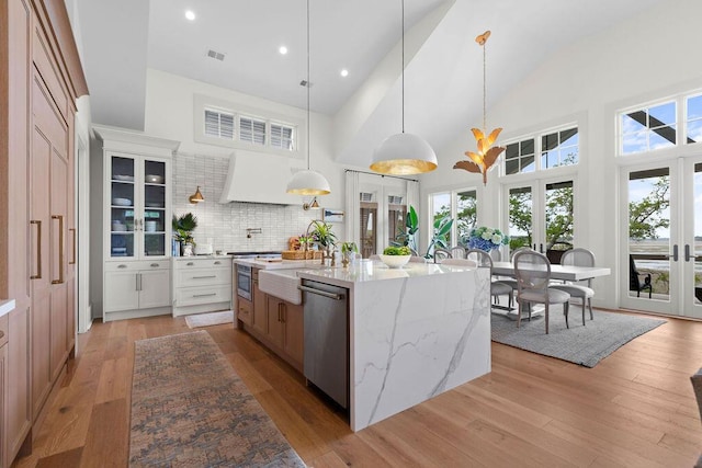 kitchen featuring a sink, high vaulted ceiling, visible vents, light wood finished floors, and stainless steel dishwasher