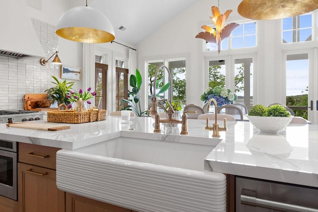kitchen featuring hanging light fixtures, decorative backsplash, custom range hood, and a sink