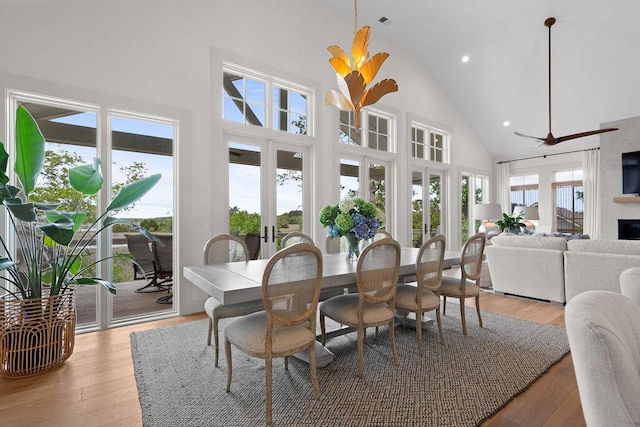 dining room with recessed lighting, light wood finished floors, high vaulted ceiling, and a large fireplace