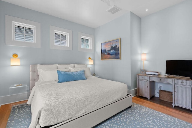 bedroom with baseboards, visible vents, and wood finished floors