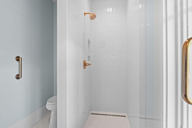 bathroom with tile patterned flooring, toilet, and tiled shower
