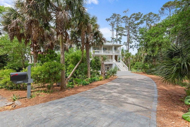 raised beach house featuring covered porch, driveway, and stairs