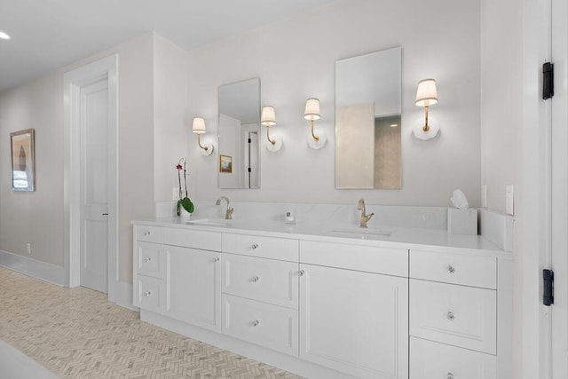 bathroom with baseboards, double vanity, and a sink