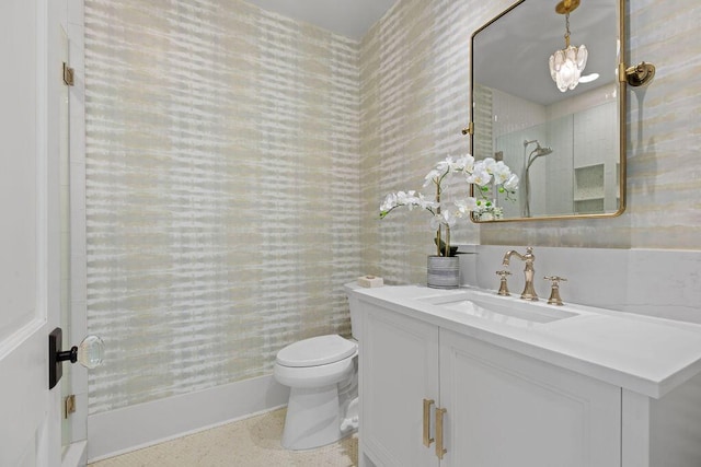 bathroom featuring toilet, walk in shower, vanity, and wallpapered walls