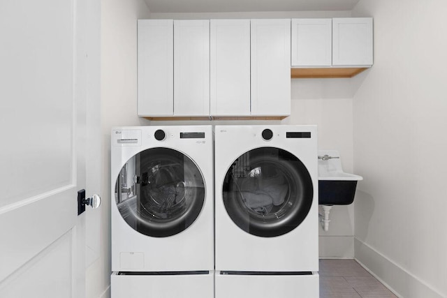 laundry room with a sink, cabinet space, washing machine and clothes dryer, tile patterned flooring, and baseboards
