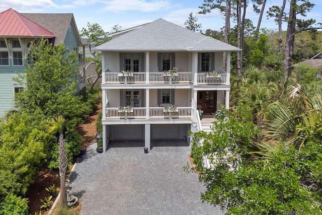 rear view of house featuring an attached garage, french doors, driveway, a balcony, and a shingled roof