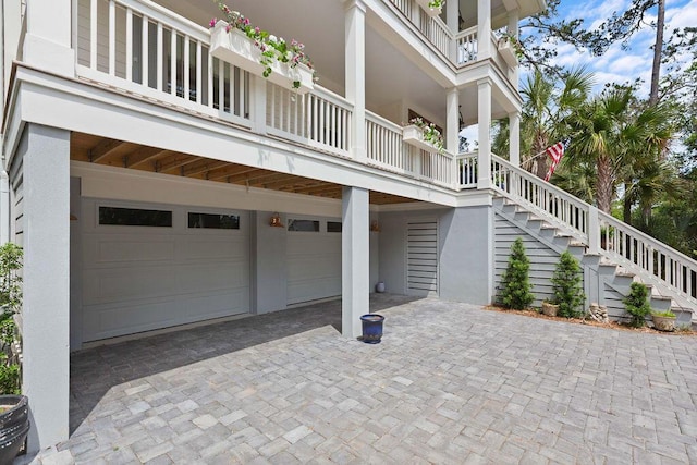 view of side of property with an attached garage, decorative driveway, stairway, and stucco siding