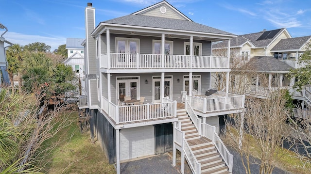 view of front facade featuring a garage, a balcony, covered porch, and french doors