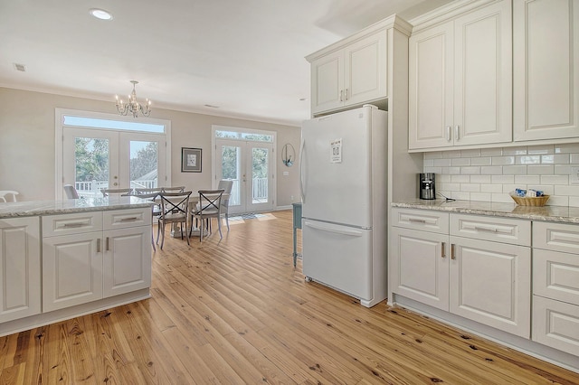 kitchen featuring white fridge, light hardwood / wood-style flooring, white cabinets, and french doors