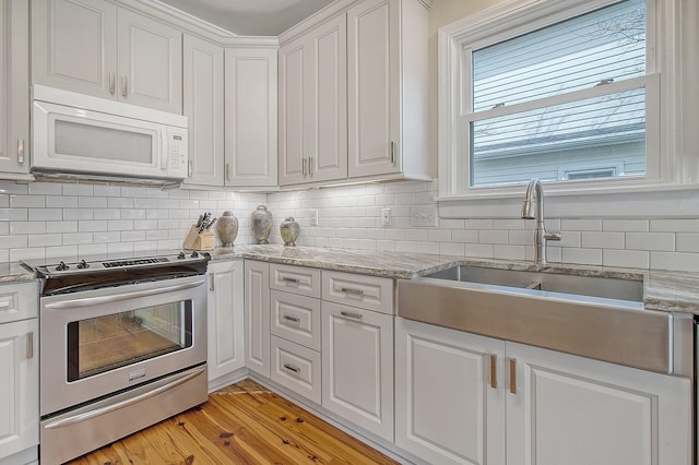 kitchen featuring white cabinetry, stainless steel range with electric stovetop, light stone countertops, and sink