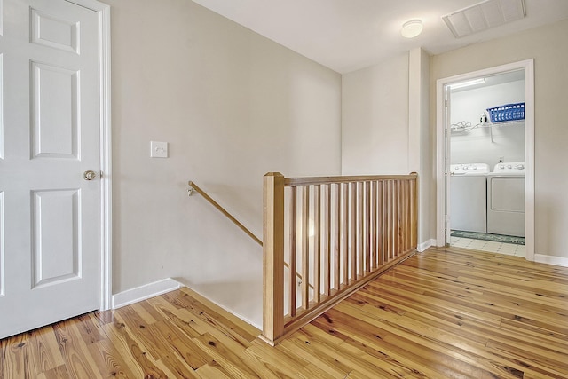 staircase with hardwood / wood-style flooring and washing machine and clothes dryer