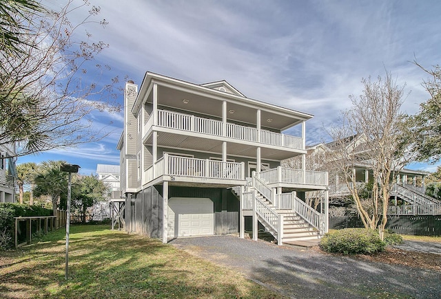 coastal home with a garage, a front yard, a balcony, and covered porch