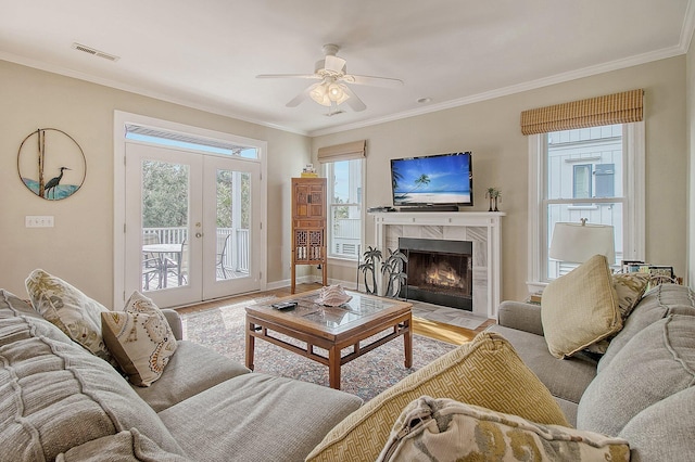 living room with french doors, a premium fireplace, and crown molding