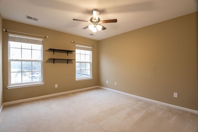 empty room with visible vents, light carpet, baseboards, and ceiling fan