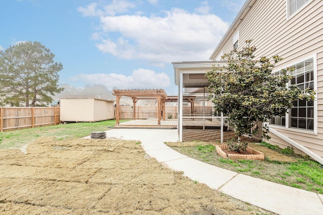 view of yard featuring an outbuilding, a shed, a wooden deck, a fenced backyard, and a pergola