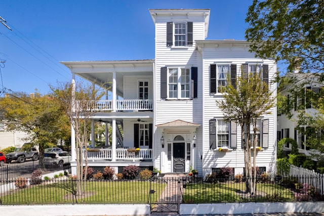 italianate-style house featuring a porch, a balcony, and a front lawn