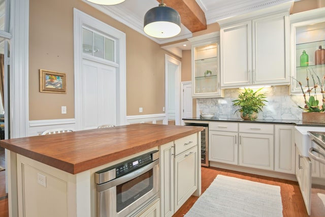 kitchen with butcher block counters, wine cooler, crown molding, and white cabinetry