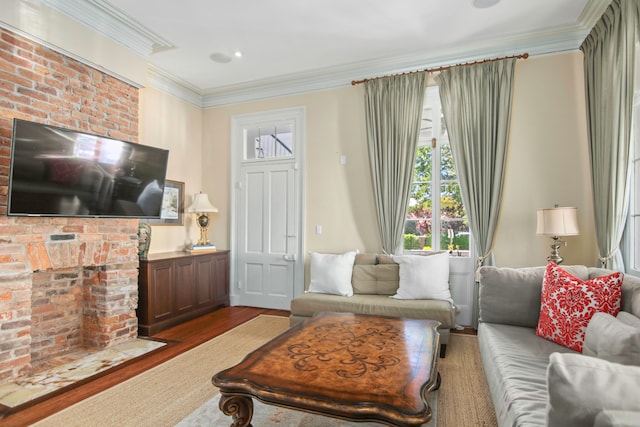 living room featuring hardwood / wood-style floors, ornamental molding, and a brick fireplace