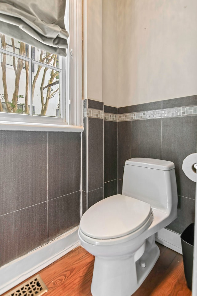 bathroom featuring wood-type flooring, tile walls, and toilet