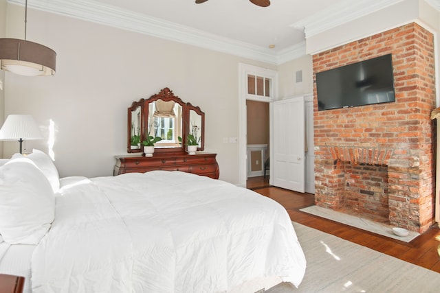 bedroom with crown molding, ceiling fan, a fireplace, and dark hardwood / wood-style flooring