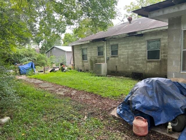 view of side of home with a lawn and central air condition unit