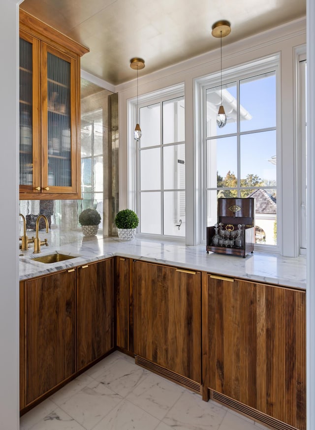 kitchen with sink, decorative backsplash, light stone countertops, and hanging light fixtures