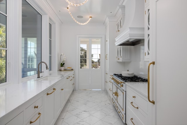 kitchen featuring premium range hood, sink, white cabinets, crown molding, and light stone countertops