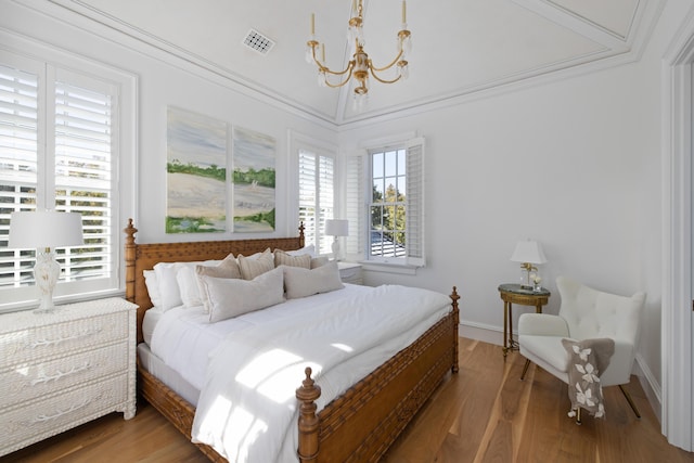 bedroom with hardwood / wood-style floors, multiple windows, and a notable chandelier