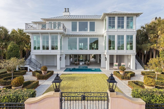 rear view of house with a patio area, a balcony, and a lawn