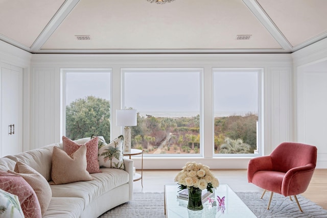 living room featuring hardwood / wood-style flooring, ornamental molding, vaulted ceiling, and a wealth of natural light