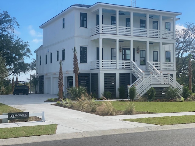 coastal inspired home featuring driveway, a balcony, ceiling fan, stairs, and a porch