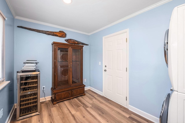foyer entrance featuring beverage cooler, wood finished floors, ornamental molding, and baseboards