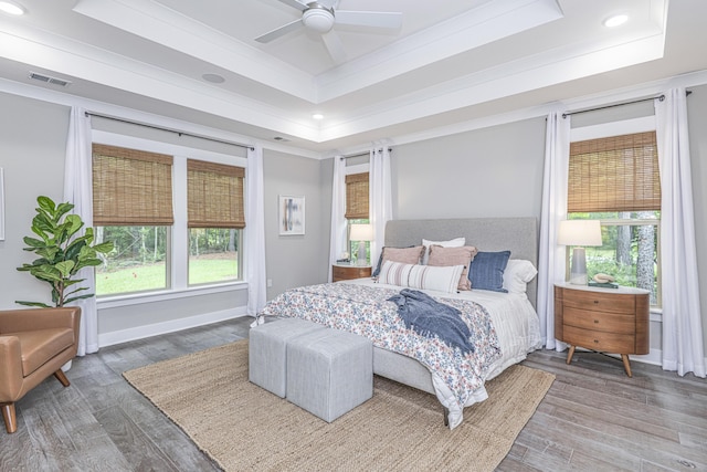 bedroom featuring a raised ceiling, ceiling fan, crown molding, and dark wood-type flooring