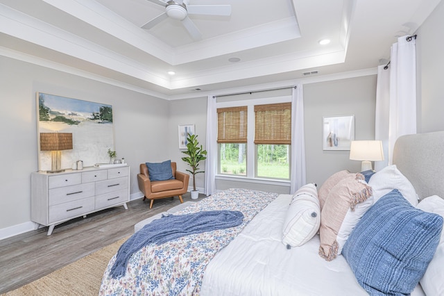 bedroom with hardwood / wood-style flooring, a raised ceiling, ceiling fan, and ornamental molding