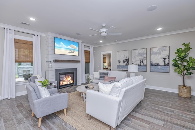 living room with crown molding, a fireplace, ceiling fan, and light hardwood / wood-style floors