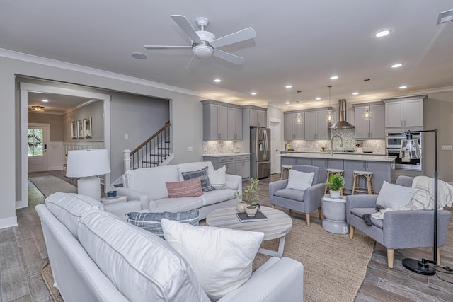 living room with ceiling fan, hardwood / wood-style floors, crown molding, and sink