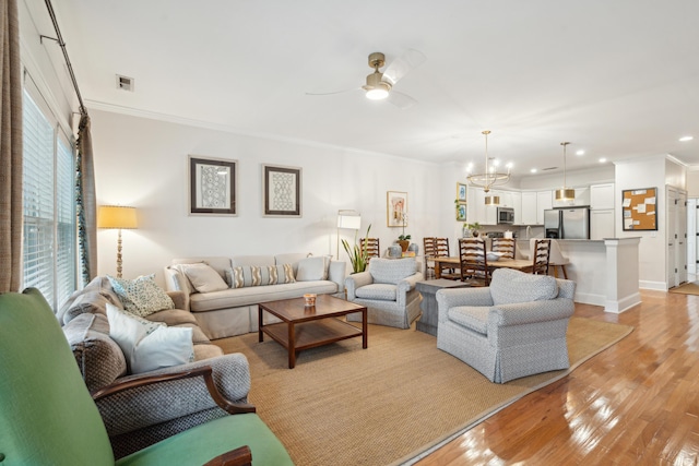 living room featuring crown molding, ceiling fan with notable chandelier, and light wood-type flooring