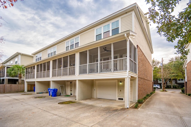 rear view of property featuring a garage, a sunroom, and ceiling fan