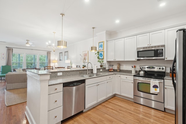 kitchen featuring appliances with stainless steel finishes, sink, pendant lighting, and white cabinets