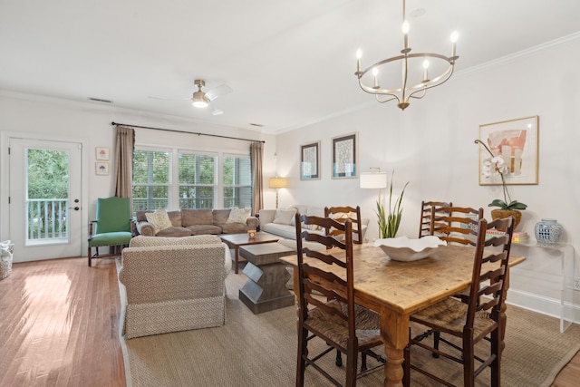 dining area with ceiling fan with notable chandelier, ornamental molding, and hardwood / wood-style floors