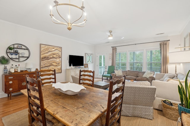 dining area featuring ceiling fan with notable chandelier, ornamental molding, and light wood-type flooring